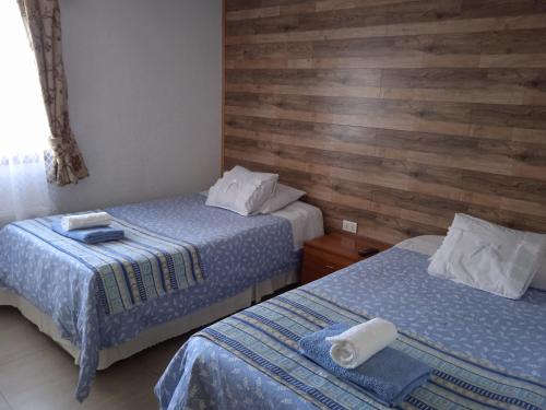 two beds in a room with wooden walls at Hostal JC in Puerto Natales