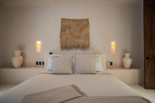 1 dormitorio con 1 cama con sábanas y almohadas blancas en Nãmas Tulum, en Tulum