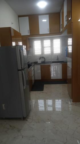 a kitchen with a refrigerator and a tile floor at DEEYA Guest House - A Luxury Home Stay in Mysore