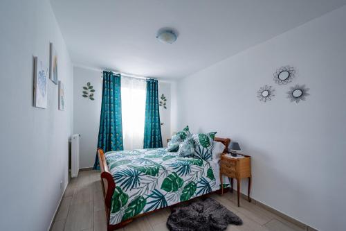 Schlafzimmer mit einem Bett mit einer blauen und grünen Tagesdecke in der Unterkunft Perle Parisienne, Vue Captivante in Saint-Ouen