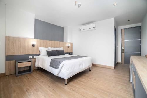a bedroom with a large white bed and a wooden floor at Hotel Plaza del Lili in Cali