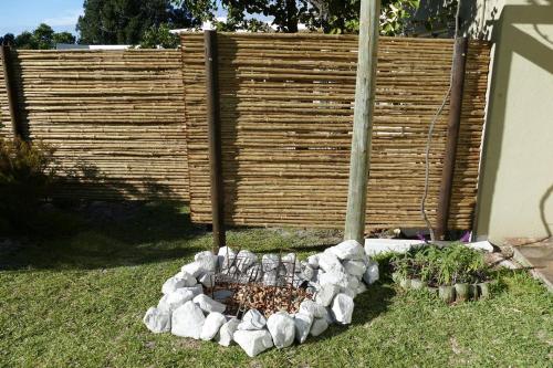 a garden with a fire pit in front of a fence at Cuckoo's Corner in Bettyʼs Bay