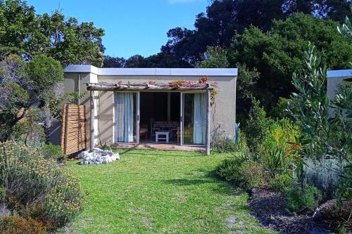 a small house with a patio and a yard at Cuckoo's Corner in Bettyʼs Bay
