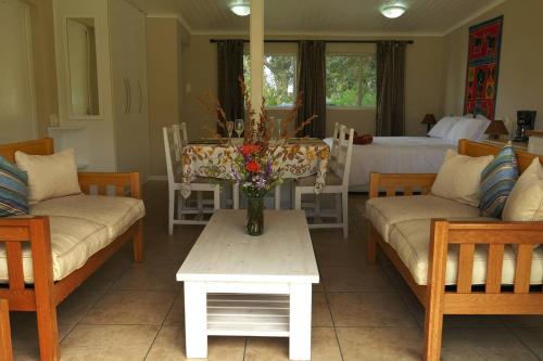 a living room with a table with a vase of flowers at Cuckoo's Corner in Bettyʼs Bay