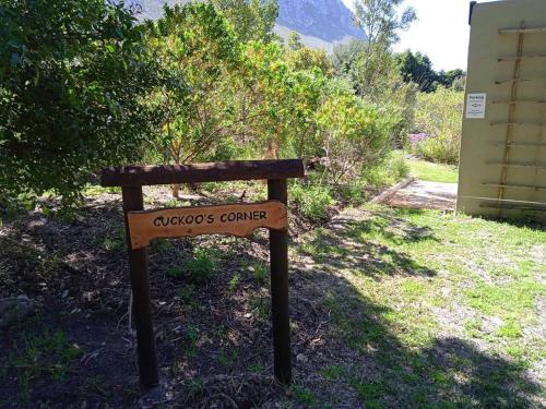 a sign sitting in the grass next to a building at Cuckoo's Corner in Bettyʼs Bay