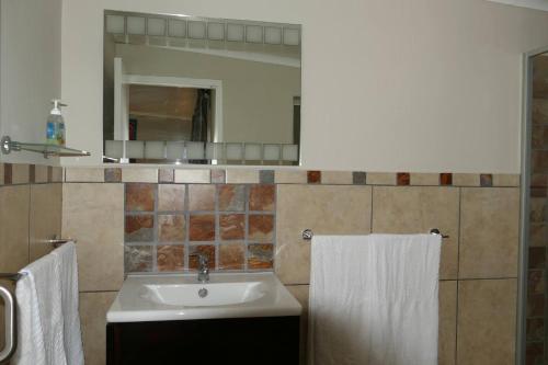 a bathroom with a sink and a mirror and towels at Cuckoo's Corner in Bettyʼs Bay