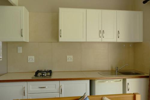 a kitchen with white cabinets and a sink at Cuckoo's Corner in Bettyʼs Bay