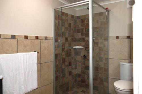 a bathroom with a glass shower with a toilet at Cuckoo's Corner in Bettyʼs Bay