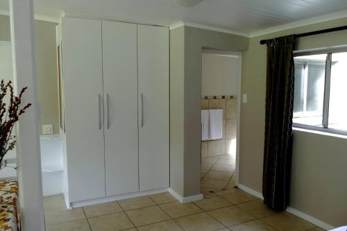 a bathroom with white cabinets and a shower at Cuckoo's Corner in Bettyʼs Bay