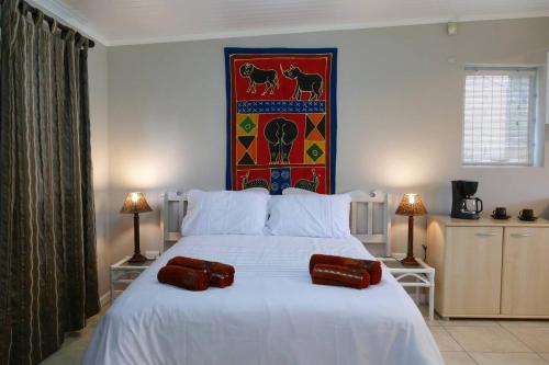 a bedroom with a white bed with two pillows on it at Cuckoo's Corner in Bettyʼs Bay