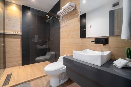 a bathroom with a white toilet and a sink at Hotel Plaza del Lili in Cali