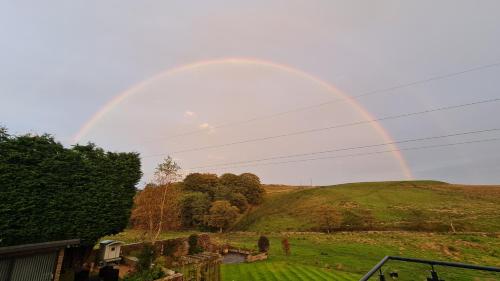 a rainbow in the sky over a green field at Cadshaw Country Views in Darwen