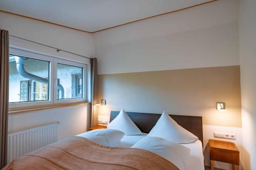ein Schlafzimmer mit einem Bett mit weißen Kissen und einem Fenster in der Unterkunft Am Hof Jungholz in Jungholz