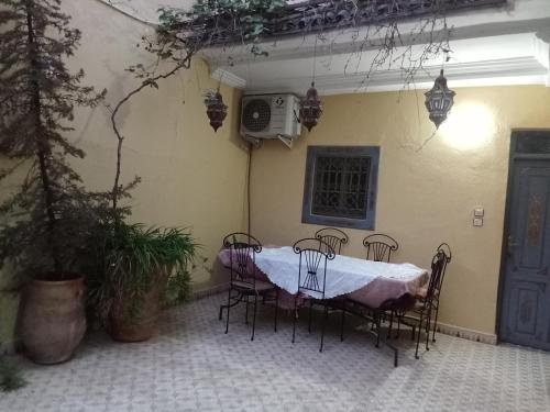 una mesa y sillas en un patio con mesa y TV en Riad taddert, en Marrakech