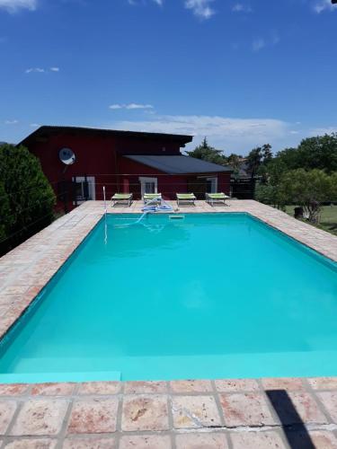 a swimming pool with blue water in front of a house at cabañas altos de giardino in Villa Giardino
