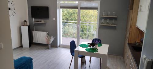 d'un salon avec une table, des chaises et une fenêtre. dans l'établissement Apartament Pod Klonem, à Bartoszyce