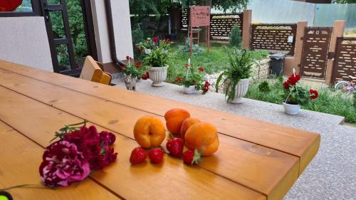 a wooden table with fruit and flowers on it at PIATRA ROSIE Pensiune Agroturistică in Niculiţel