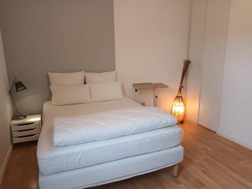 un letto bianco in una stanza con lampada di résidence la clairière aux portes de la baie de Somme a Abbeville