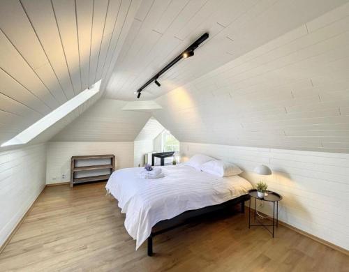 - une chambre mansardée avec un lit blanc dans l'établissement Residence Dunes et Mer, à Coxyde