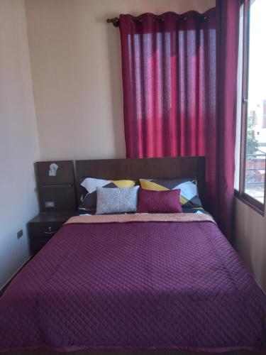 um quarto com uma cama com lençóis roxos e uma janela em El Molino Lodging/Restaurant em Torotoro