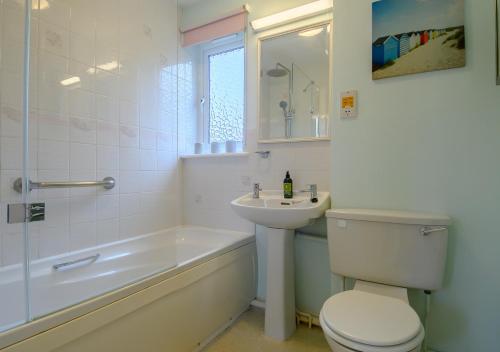 a bathroom with a toilet and a sink and a bath tub at Rainbow Cottage in Thorpeness