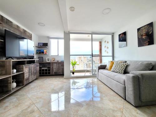 a living room with a couch and a television at Modern High-Rise 2/2 Apartment with City View. in Sabaneta