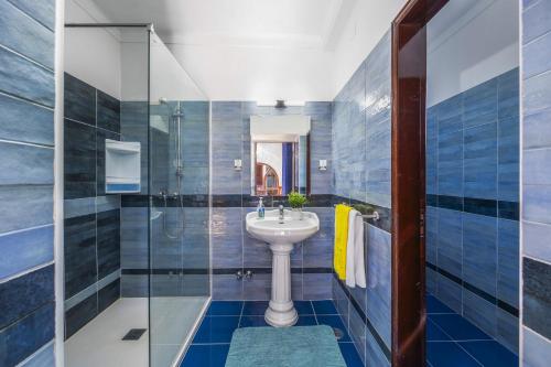 La salle de bains est pourvue d'un lavabo et d'une douche en verre. dans l'établissement Villa Leoes by Villa Plus, à Carvoeiro