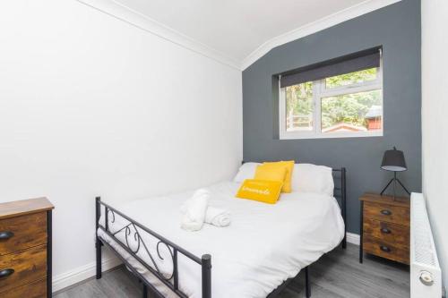 Un dormitorio con una cama con almohadas amarillas y una ventana en 'The Lodge' Bedworth, en Bedworth