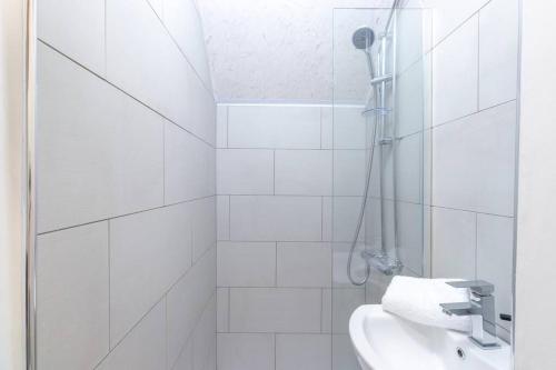 a white bathroom with a shower and a sink at 'The Lodge' Bedworth in Bedworth