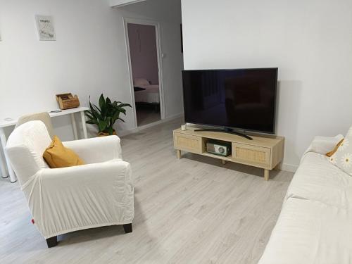 ein Wohnzimmer mit 2 weißen Stühlen und einem Flachbild-TV in der Unterkunft Casa Remes in Sagunt