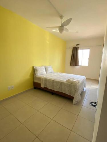 1 dormitorio con cama y pared amarilla en Relaxe e curta num duplex completíssimo, en Lauro de Freitas