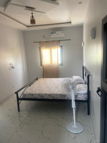Schlafzimmer mit einem Bett und einem Ventilator auf dem Boden in der Unterkunft Mondialaw in Toubab Dialao