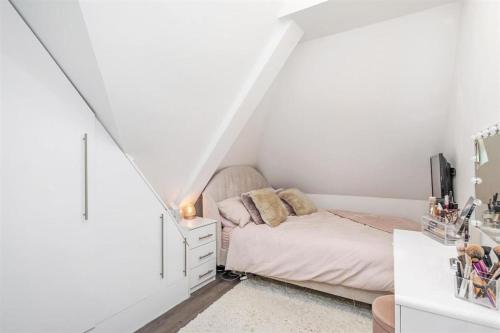 a small white bedroom with a bed and a dresser at Solihull Town Centre Spacious Studio Apartment in Solihull