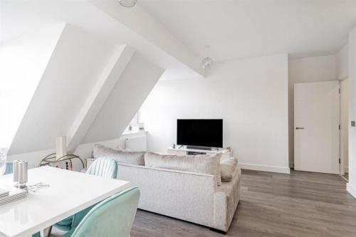 a white living room with a couch and a tv at Solihull Town Centre Spacious Studio Apartment in Solihull