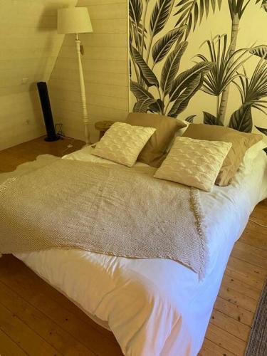 a bed with white sheets and pillows in a room at Appartement en campagne in Berville-sur-Mer