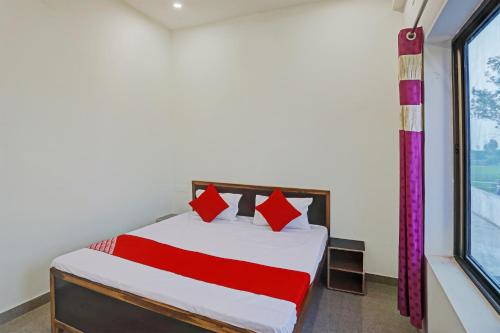 a bedroom with a bed with red pillows and a window at OYO Flagship Hotel Bhardwaj in Varanasi