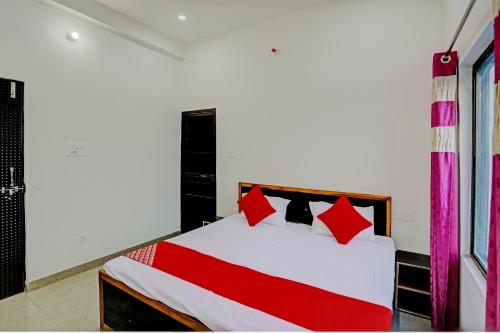 a bedroom with a white bed with red pillows at OYO Flagship Hotel Bhardwaj in Varanasi