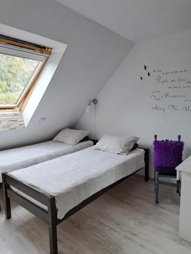 2 Betten in einem Zimmer mit Fenster und Wandschreiben in der Unterkunft Soba Erika in Fužine