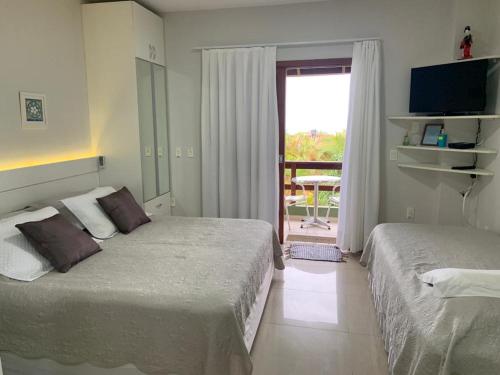 フロリアノポリスにあるPousada Mar de Cristalのベッド2台とバルコニーが備わるホテルルームです。