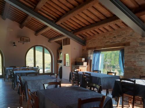 uma sala de jantar com mesas e cadeiras azuis e janelas em Agriturismo Antica Corte em Montatteglia