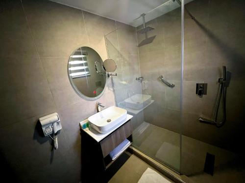 a bathroom with a sink and a shower with a mirror at IKOGOSI WARM SPRINGS RESORT in Ikogosi