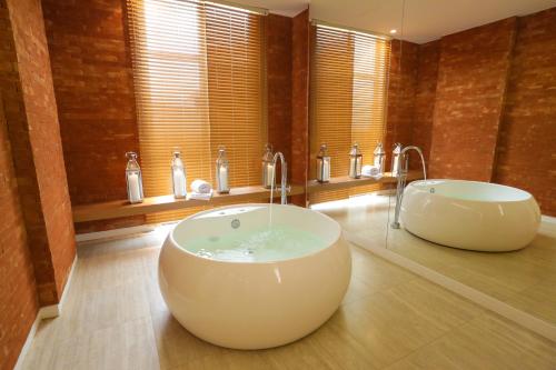 a bathroom with two sinks and a bath tub at Vista Park Hplus Long Stay in Brasília