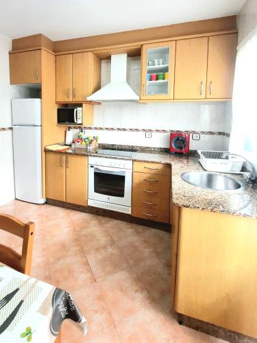 a kitchen with wooden cabinets and a sink and a refrigerator at Apartamento Obao in Ribadeo