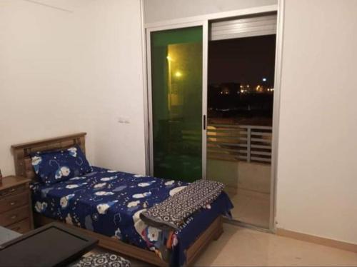 1 dormitorio con 1 cama y puerta corredera de cristal en Sidi rahal chat, en Sidi Rahal