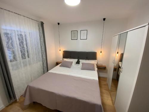 a bedroom with a white bed and a window at Apartman "Borićevac" in Sinj