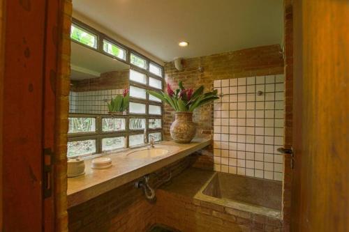 La salle de bains est pourvue d'un lavabo et d'un vase de fleurs. dans l'établissement Casa Praia da Feiticeira Condomínio Fechado, à Ilhabela
