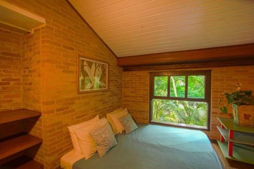 Habitación con cama en una pared de ladrillo en Casa Praia da Feiticeira Condomínio Fechado, en Ilhabela