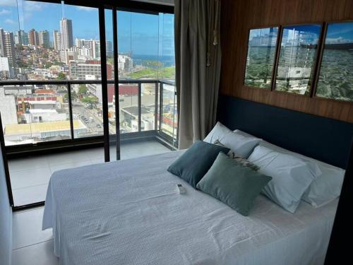 a bedroom with a bed with a view of a city at Salvador farol da barra 01 Apartamento Vista Mar in Salvador