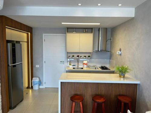 a kitchen with a counter and two stools in it at Salvador farol da barra 01 Apartamento Vista Mar in Salvador