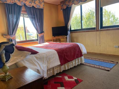a bedroom with a bed and a tv and windows at Hostal Buenaventura in Valdivia